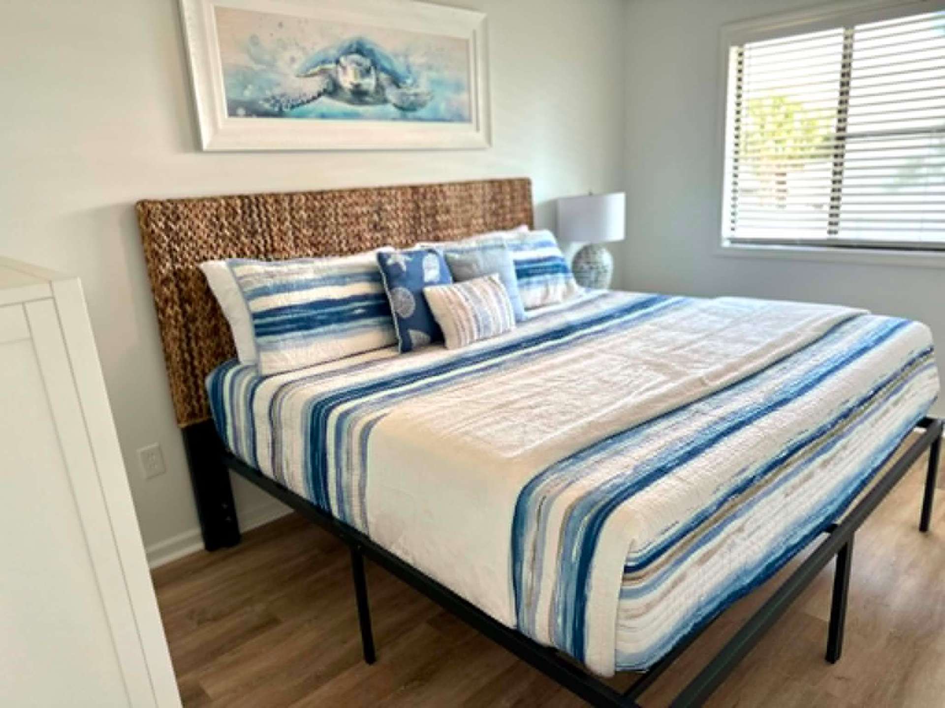 Coastal bedroom with woven headboard and striped bedding, freshly cleaned