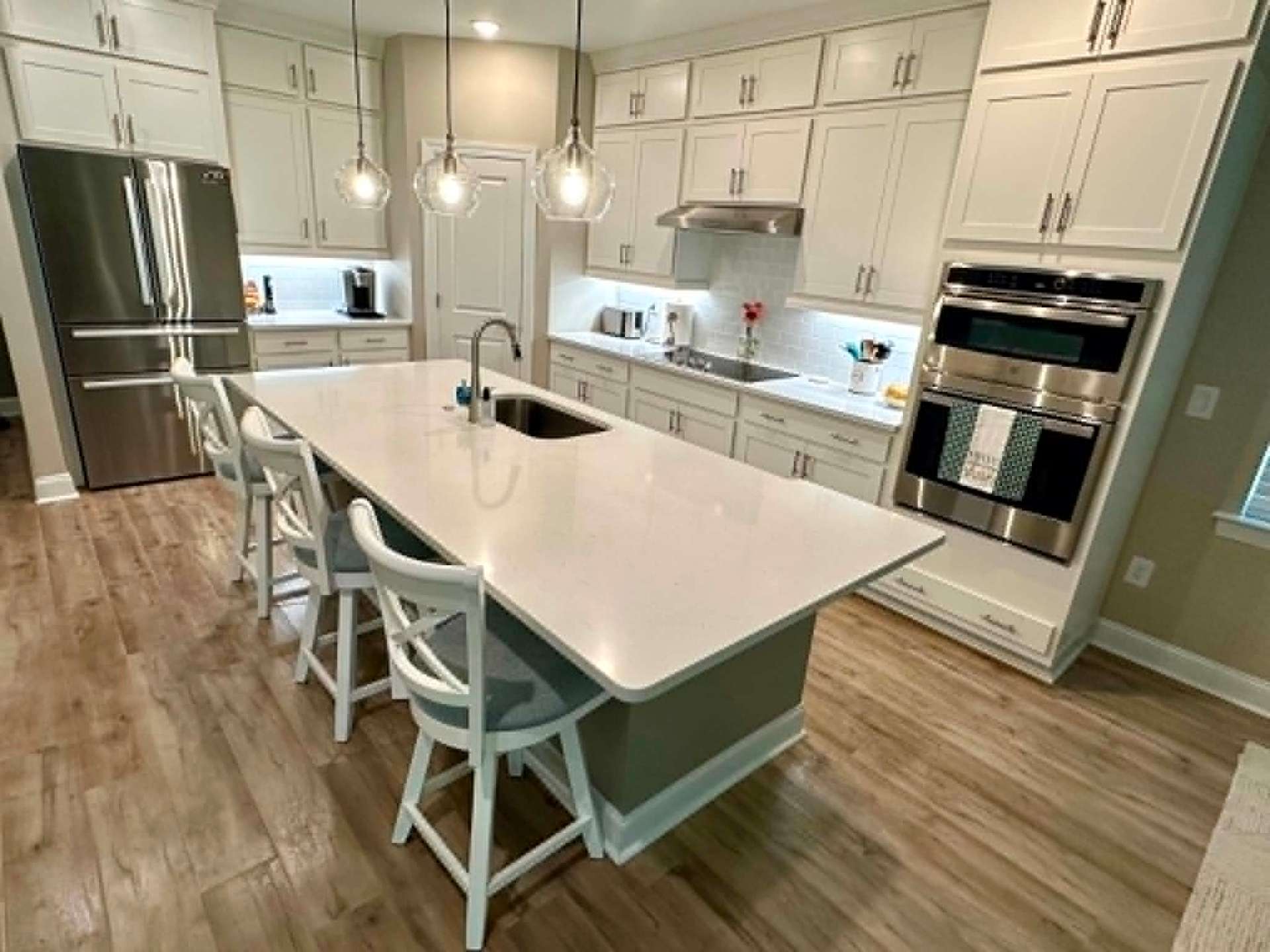 Bright white kitchen with large island and pendant lights, freshly cleaned
